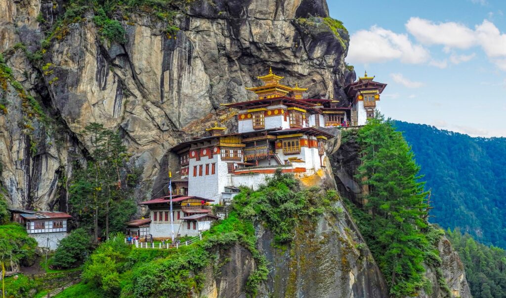 A stunning view of Taktsang Monastery, also known as the Tiger's Nest, clinging to the cliffside amidst lush greenery.