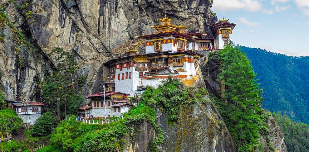 101 A stunning view of Taktsang Monastery, also known as the Tiger's Nest, clinging to the cliffside amidst lush greenery.