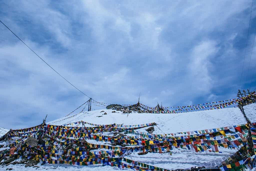 Panoramic vista from Chele La Pass, capturing snow-capped peaks of the Himalayas and winding mountain roads.